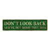 A vintage metal sign with green lettering that reads Don't look back you're not going that way