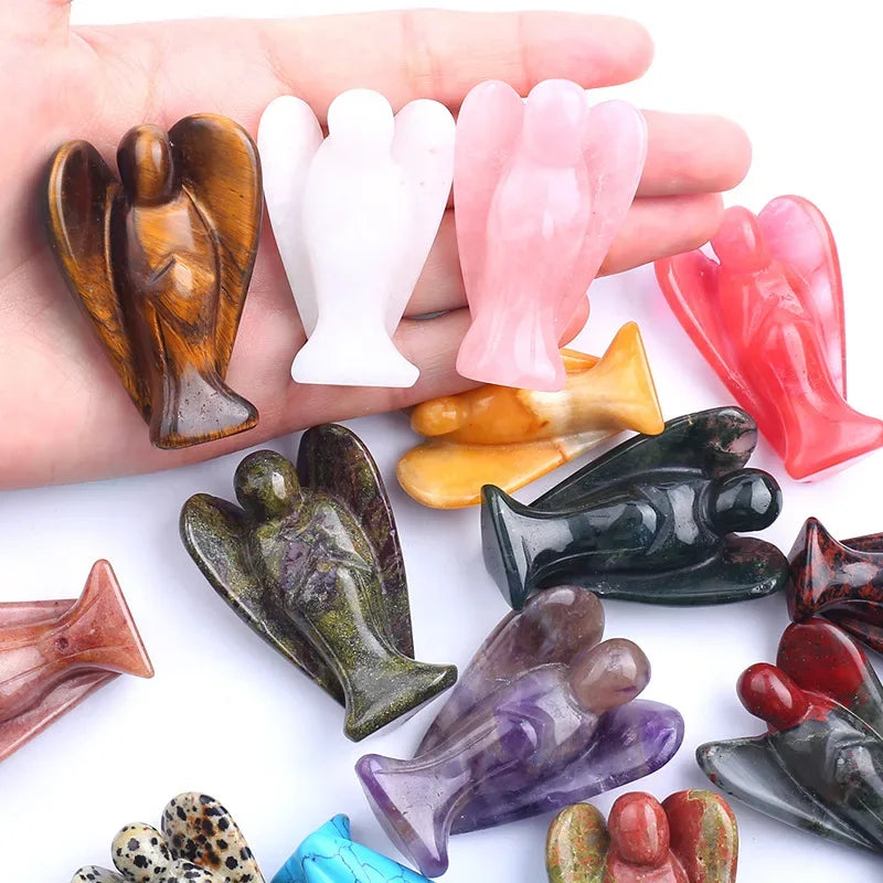Hand-carved angel crystal figurines in various colors and shapes held in a hand.