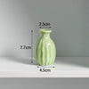 A light green ceramic mini vase with a rounded body and narrow neck, shown against a white background.