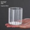 A clear cylindrical glass vase with vertical ridges is held in a hand.