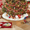 A decorated Christmas tree with red and white garland, surrounded by gifts and a wooden train set.