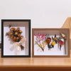 A wooden shadow box frame containing dried floral arrangements and keepsakes.