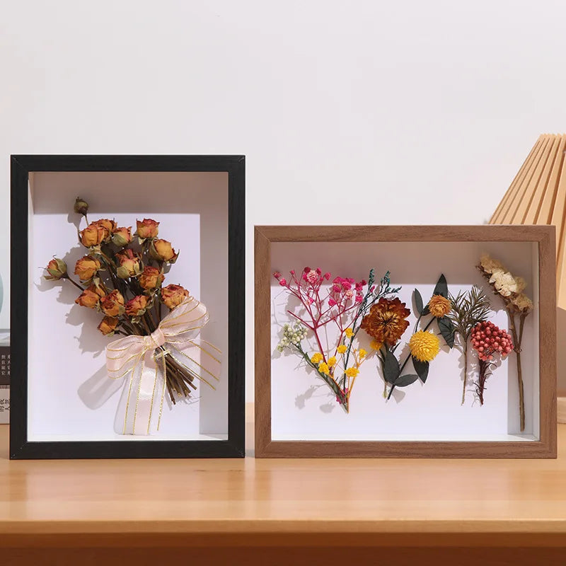 A wooden shadow box frame containing dried floral arrangements and keepsakes.