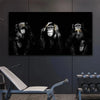 A dark canvas wall art print featuring three silhouettes of monkeys against a black background.
