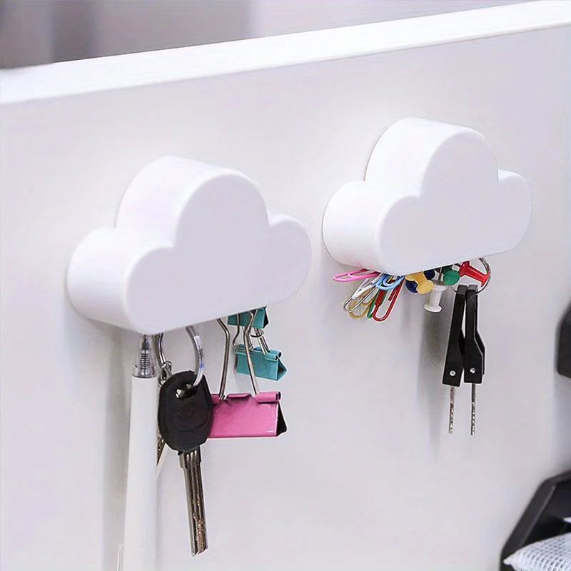 White magnetic cloud key hanger displaying various keys and small accessories on a white wall.