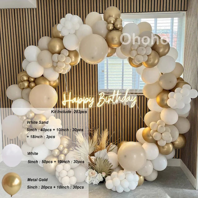 A balloon garland arch made of white, beige, and gold latex balloons displayed indoors.