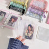 A hand holds a glitter star card binder with various clear plastic storage sheets and a pink cover.