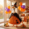 A decorative Halloween lawn goose costume featuring an orange body, black cape, and witch hat, displayed indoors near a windo