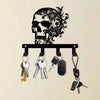 Black iron skull wall hook with floral accent holding various keys