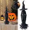 Estatua de bruja gótica gris oscura con sombrero ancho y túnicas fluidas junto a una calabaza naranja.