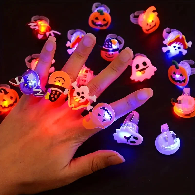 A hand holds a collection of glowing Halloween-themed rings, including pumpkins and ghosts, against a dark background.