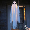 A white ghost decoration with an LED light is hanging against a dark wooden door.