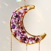 A golden dreamcatcher sun catcher featuring purple and pink crystals hanging from a wire frame.