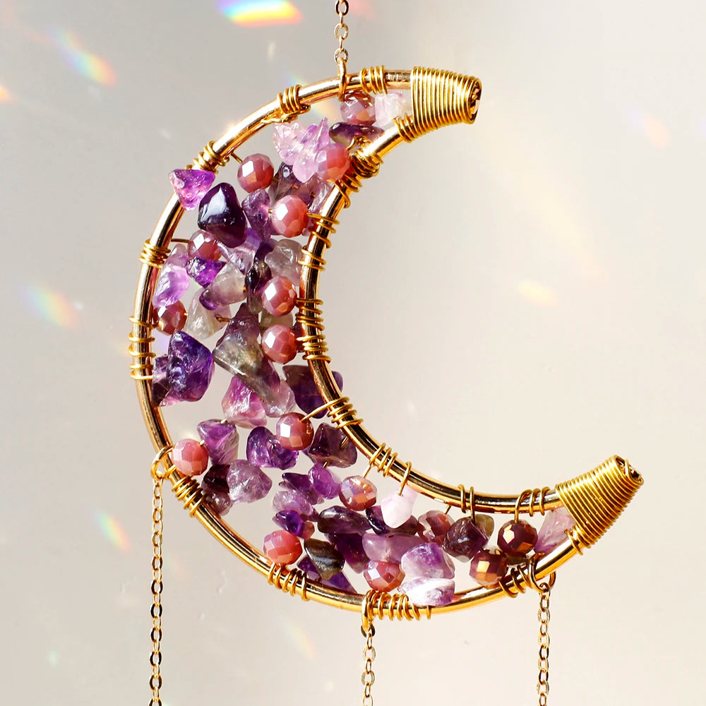 A golden dreamcatcher sun catcher featuring purple and pink crystals hanging from a wire frame.