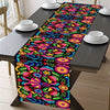 Vibrant floral print linen table runner displayed on a dark wooden table set for a fiesta celebration.