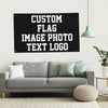 A black sign with white text that reads Custom Flag Image Photo Text Logo hanging on a wall above a gray sofa.