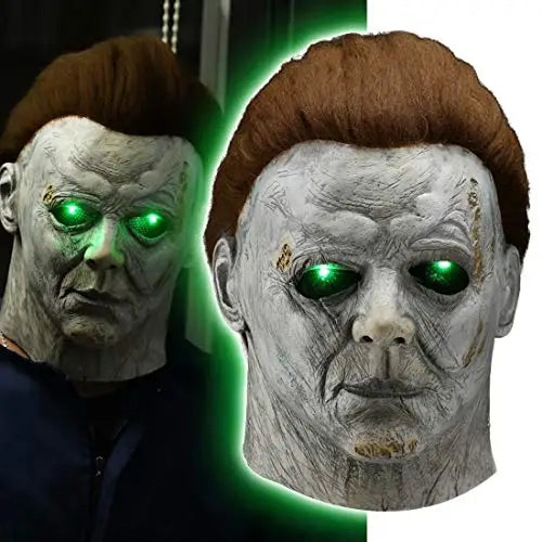 A close-up of a classic Michael Myers horror mask with green glowing eyes, displayed against a dark background.