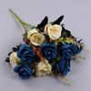 A bouquet of artificial silk roses in shades of blue and cream with dark green foliage.