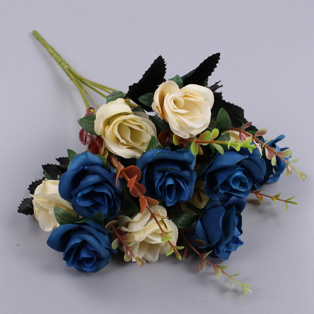 A bouquet of artificial silk roses in shades of blue and cream with dark green foliage.