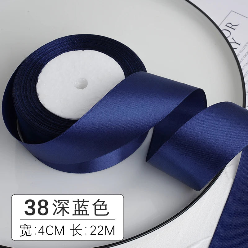 Un rouleau de ruban décoratif en satin bleu foncé avec un cœur blanc et les spécifications du produit ci-dessous.
