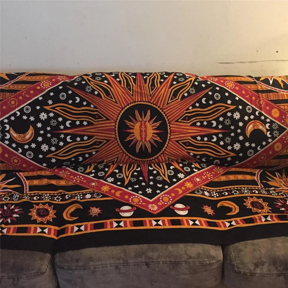 A close-up of a Bohemian mandala tapestry wall hanging featuring orange, yellow, and white patterns on a black background.