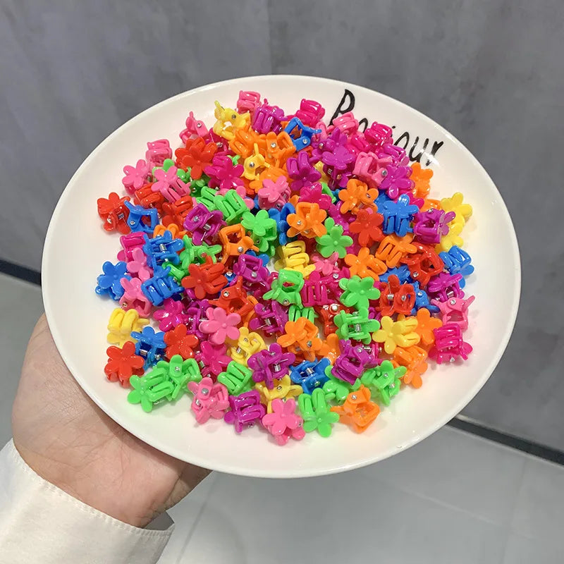 A pile of colorful flower and star hair claw clips for kids on a white plate.