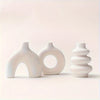 A set of three smooth, white ceramic vases with varying organic shapes and textures.
