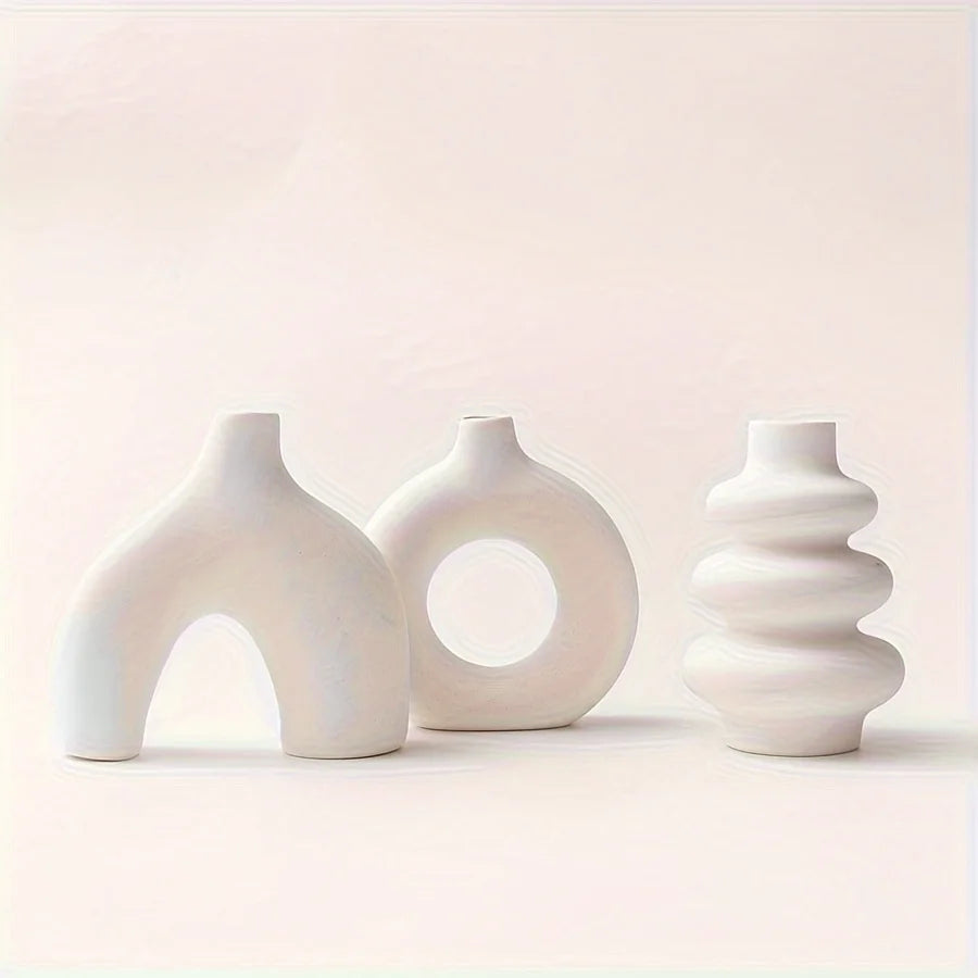 A set of three smooth, white ceramic vases with varying organic shapes and textures.