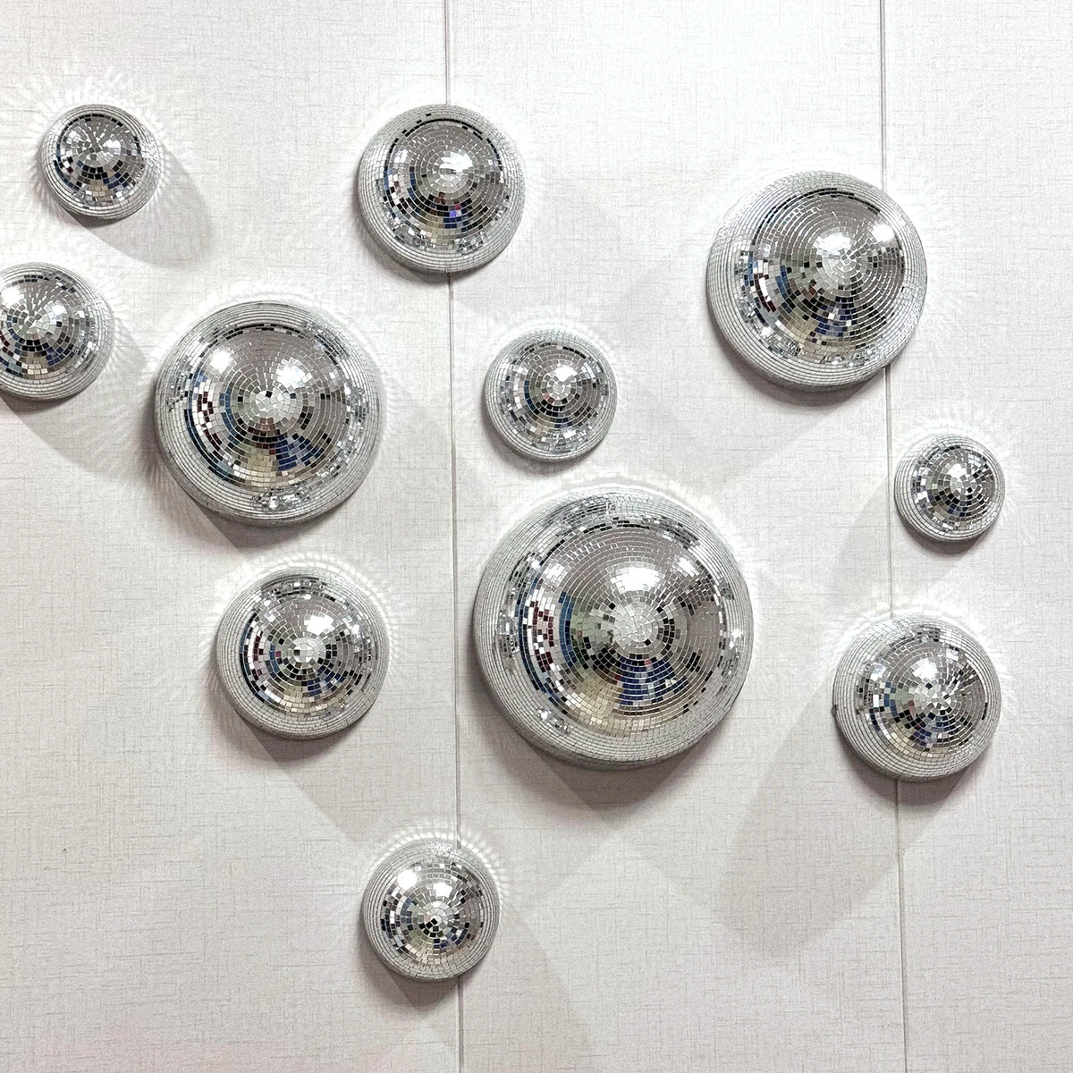A collection of silver disco balls mounted on a white surface.