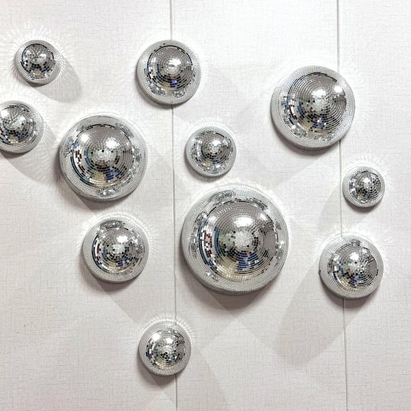 A collection of silver disco balls mounted on a white surface.