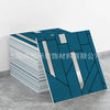 A stack of blue and white marble peel-and-stick tile stickers with gold accents displayed on a gray surface.