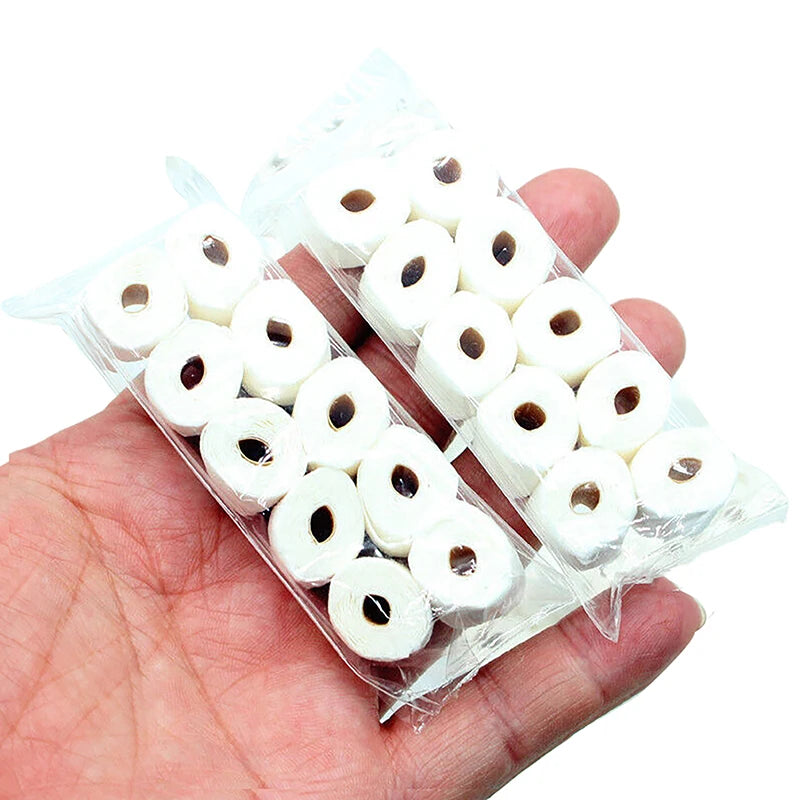 Une main tient un emballage plastique transparent rempli de rouleaux miniatures de papier toilette blanc pour décoration de m