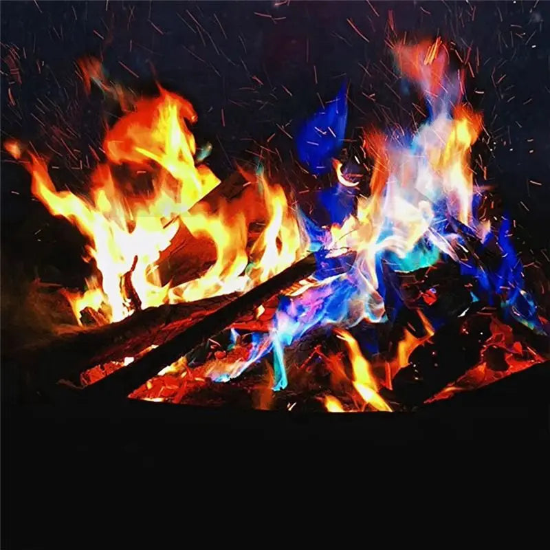 A close-up of colorful fire packets burning outdoors, creating bright flames and sparks against a dark background.
