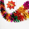 A shimmering tinsel garland ribbon featuring red, orange, yellow, and green leaves for holiday decor.