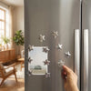 A hand places a silver star magnet onto the door of a stainless steel refrigerator.