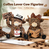 A brown cow figurine holding a sign with coffee beans and a book, set on a wooden surface.