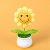Handmade knitted yellow sunflower with green leaves growing in a white pot