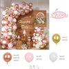 A large balloon garland featuring rose gold and pink latex balloons arranged on a wooden surface.