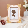 A delicate gold-framed photo frame with a light pink background and a silhouette of a woman's profile.