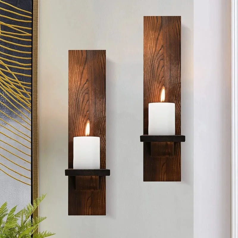 Two vertical wooden wall candle holders with white candles mounted on a light gray wall.