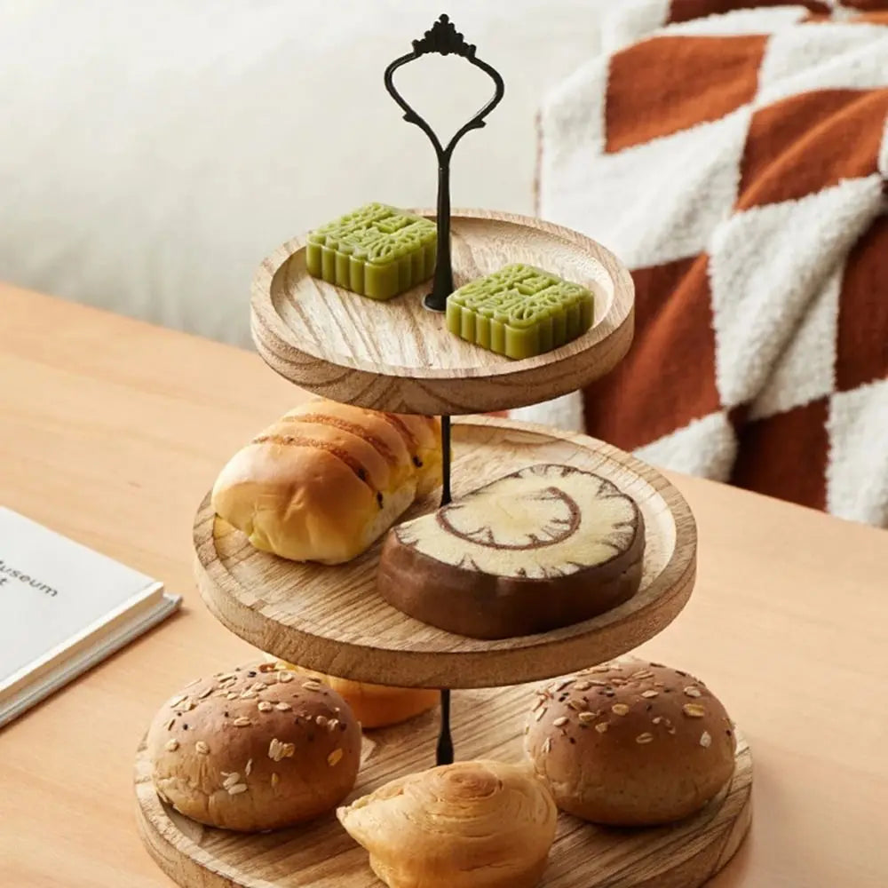 A wooden 3-tier cupcake stand displaying various baked goods including cupcakes, a pastry, and buns.