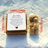 A small brown plush bear sits next to an open gift box with a handwritten encouraging message.