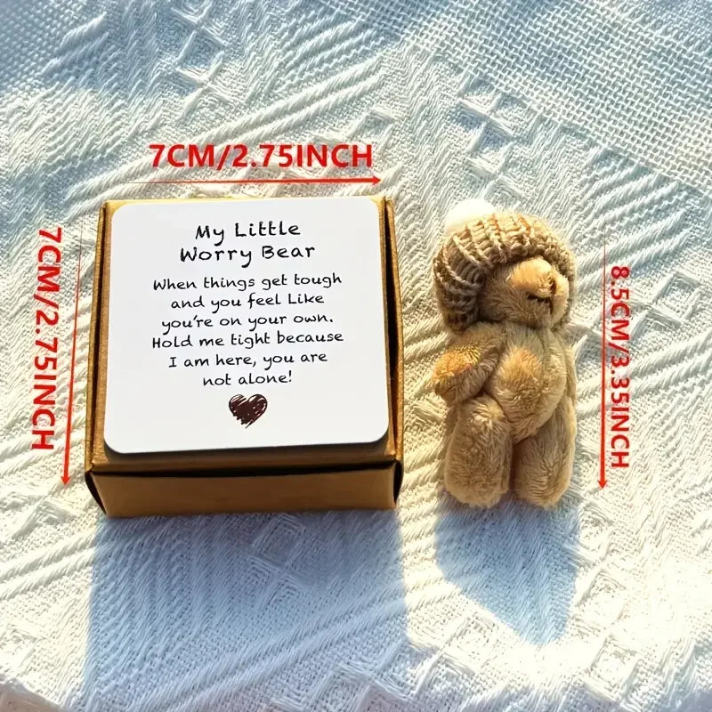 A small brown plush bear sits next to an open gift box with a handwritten encouraging message.