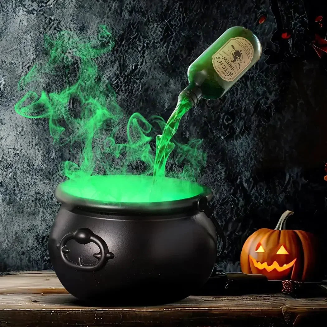 A black witch cauldron emitting green fog mist on a wooden surface.