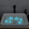 A white bathroom sink with glowing blue sea turtle decals and a black faucet.