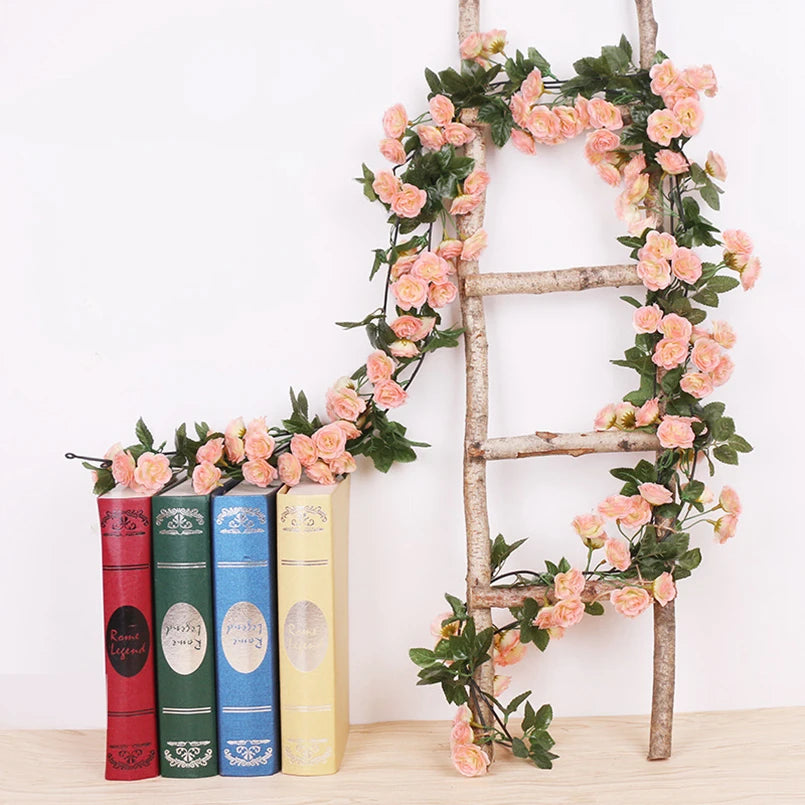 A wooden ladder decorated with a silk rose vine garland featuring pink and green roses.