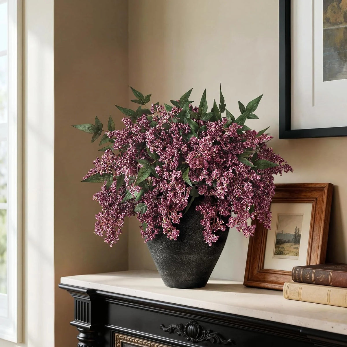 A bouquet of artificial nandina berry stems in dusty plum color displayed in a dark vase on a mantelpiece.
