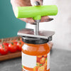 A hand holds a bright green adjustable stainless steel jar opener above an orange-colored glass jar.