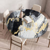 A round table with a black and gold marble print top set for dining.