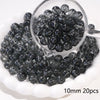 A clear glass container filled with small, dark gray spacer beads for jewelry making
